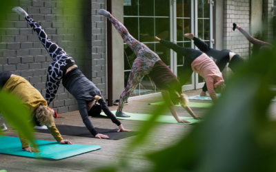 Yoga class does 3-legged dog outside a studio