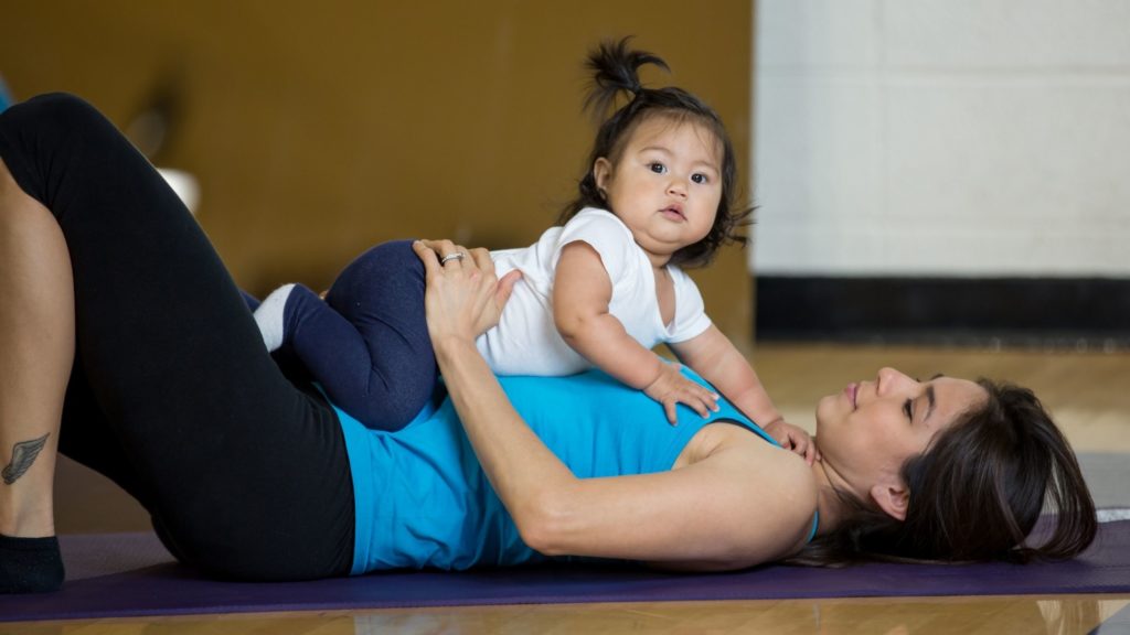 Baby lies on mom's tummy in a yoga class