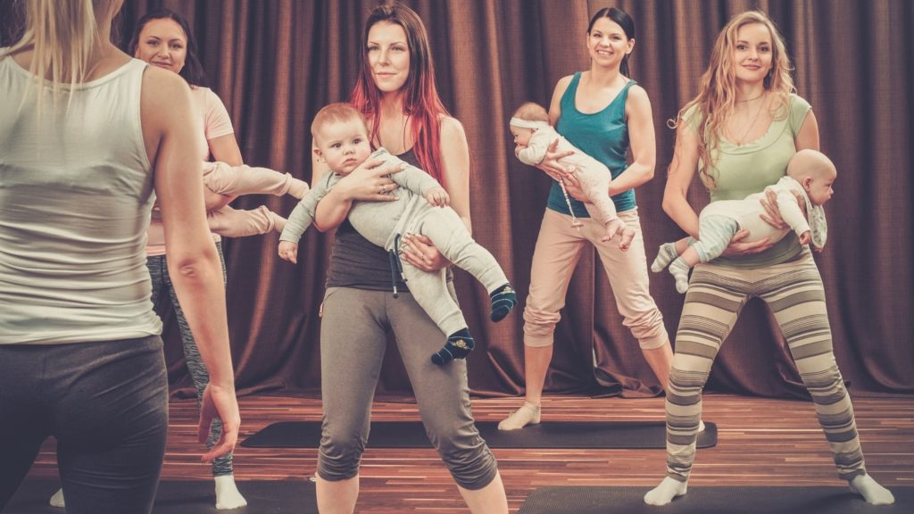 4 moms carrying babies and standing on yoga mats